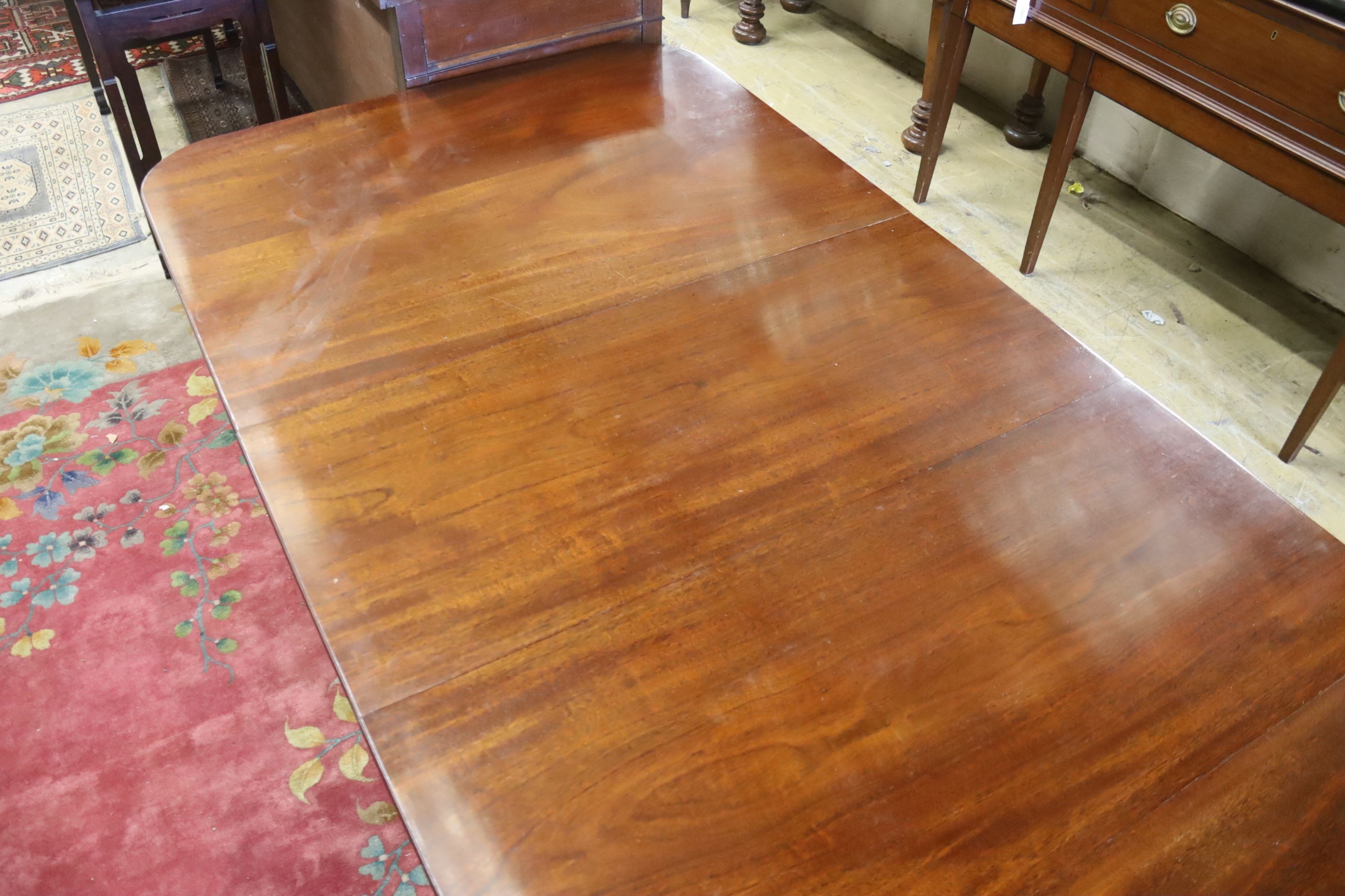 A reproduction George III style mahogany twin pillar extending dining table, two spare leaves, length 244cm extended, width 107cm, height 72cm